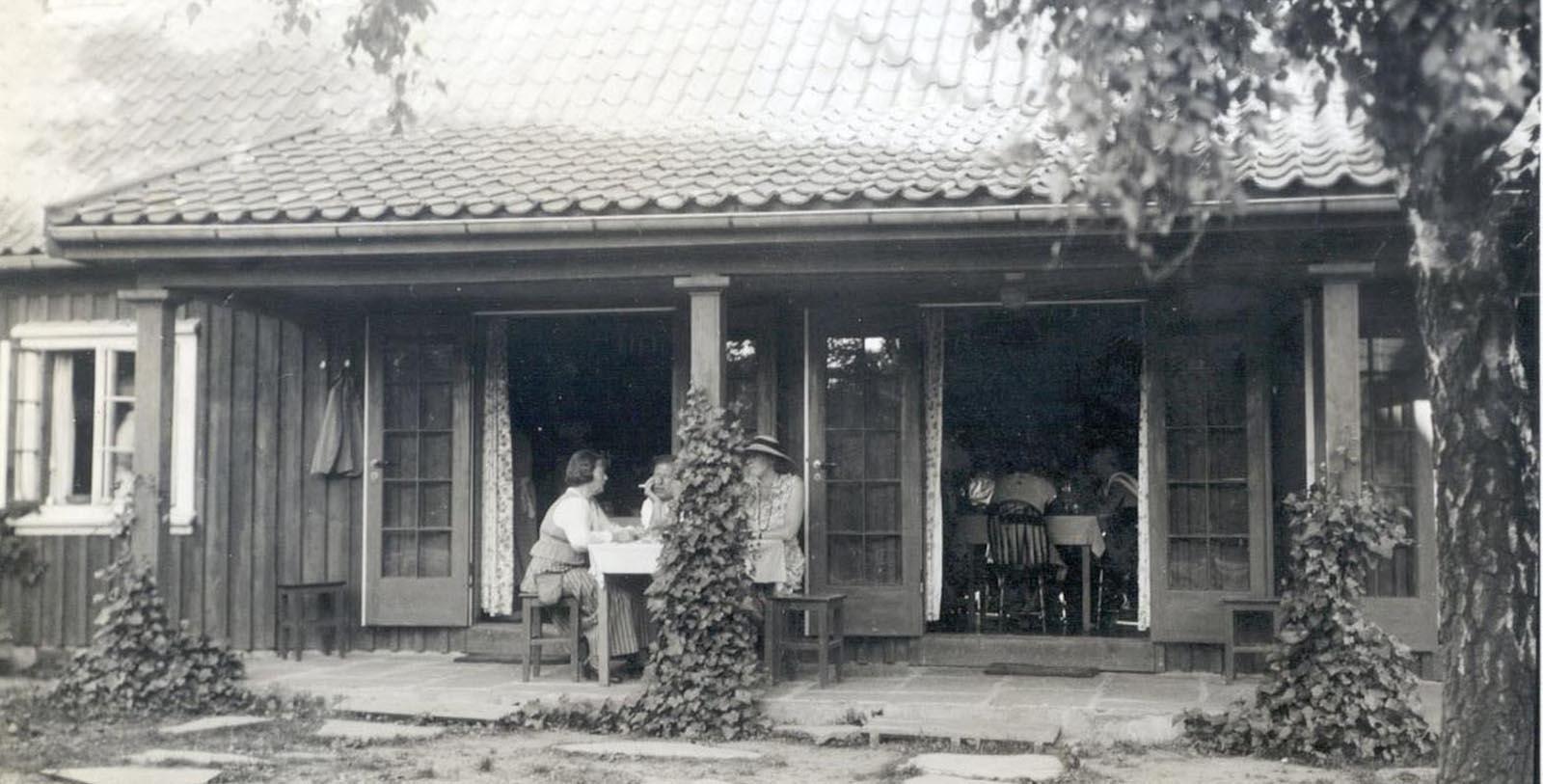 a group of people sitting at a table outside a house
