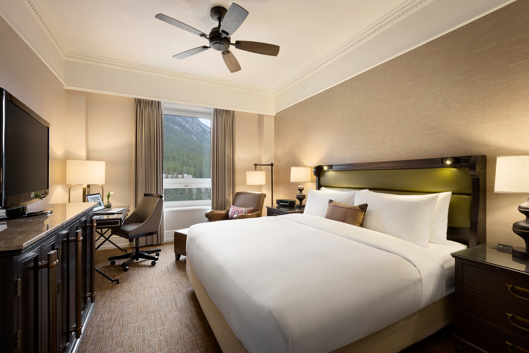 a room with a bed and a desk and a fan
