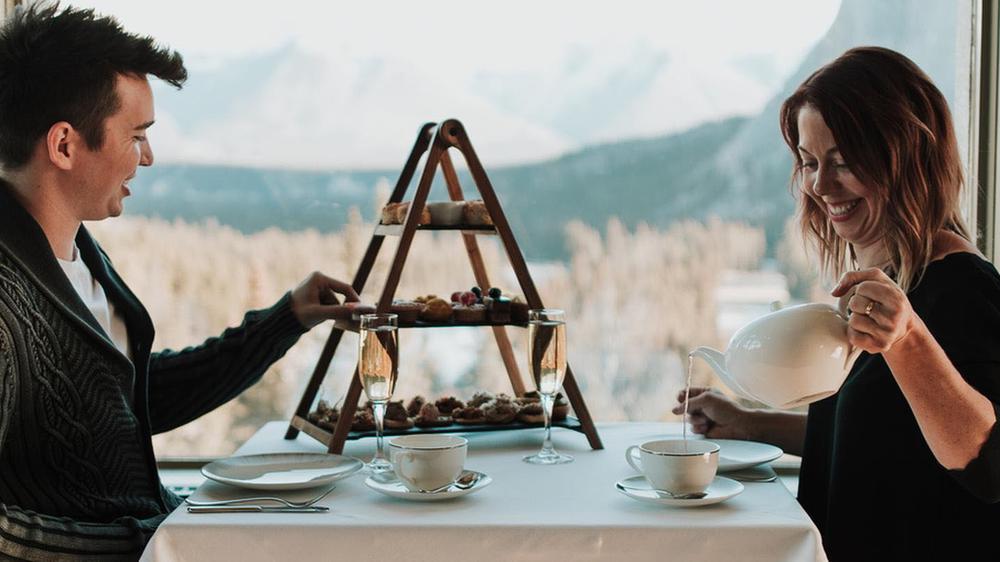 a couple of people sitting at a table with a pyramid shaped tray with food