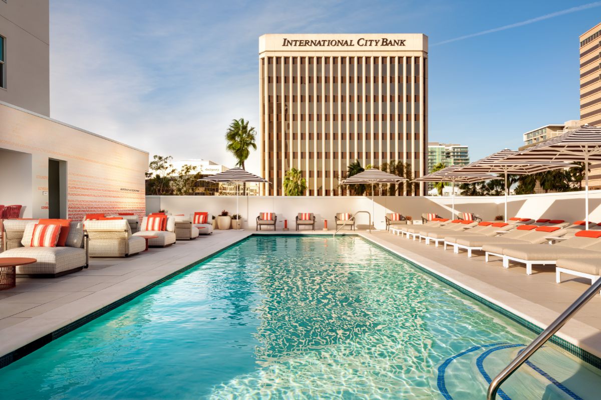 a pool with lounge chairs and umbrellas in front of a building