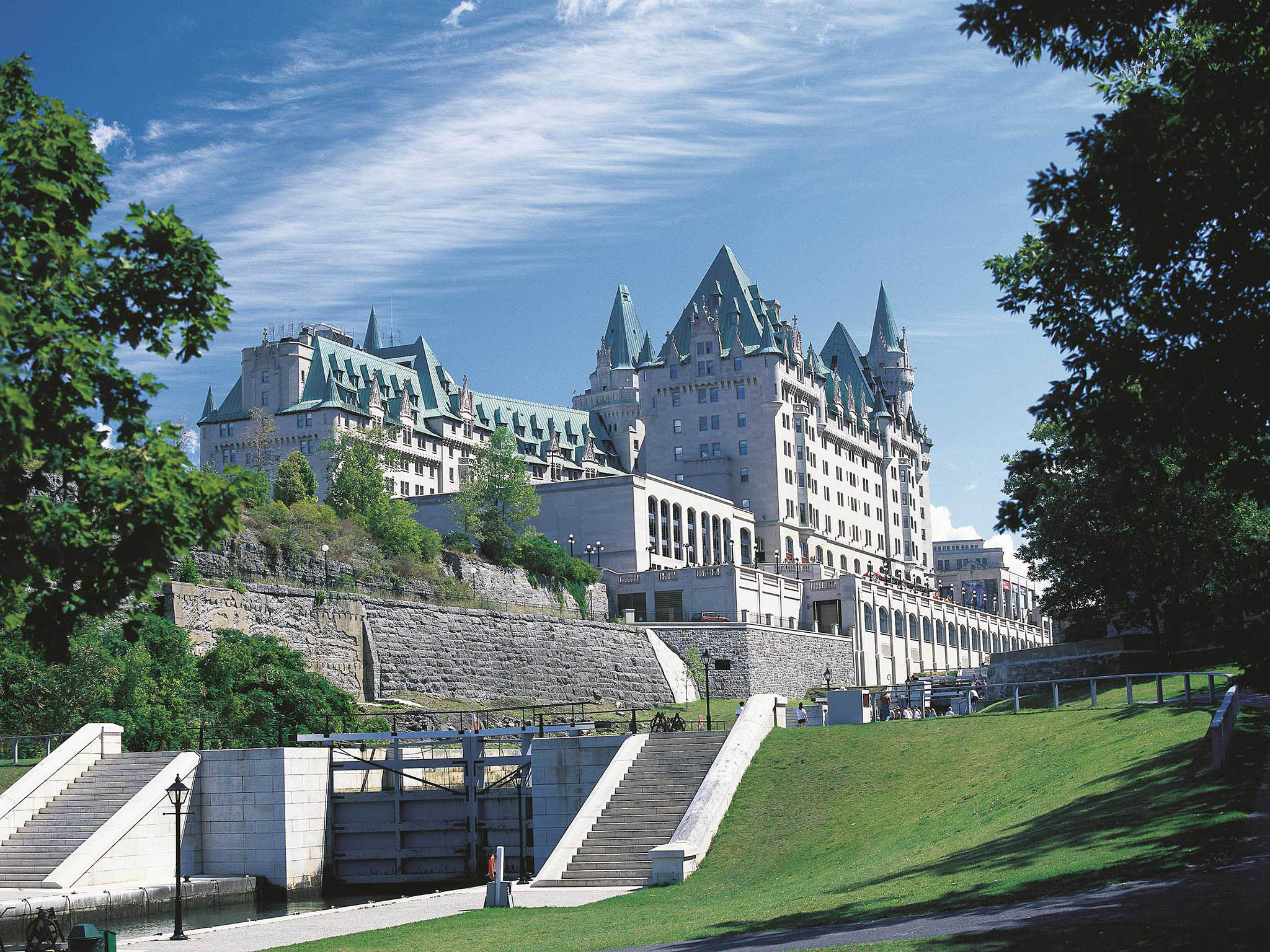a large building with a green lawn and a river