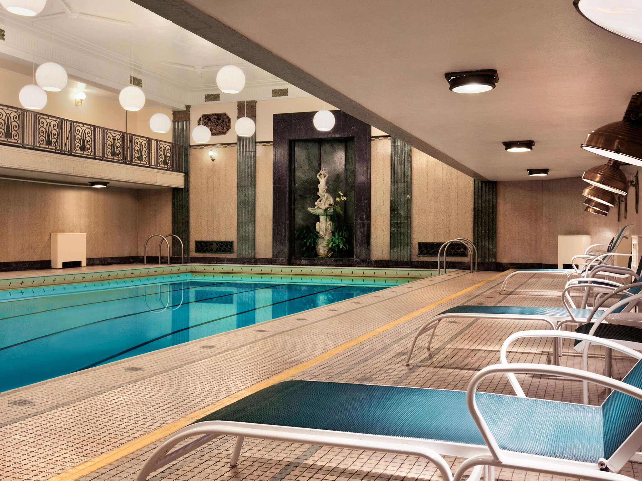 a swimming pool with chairs and a railing
