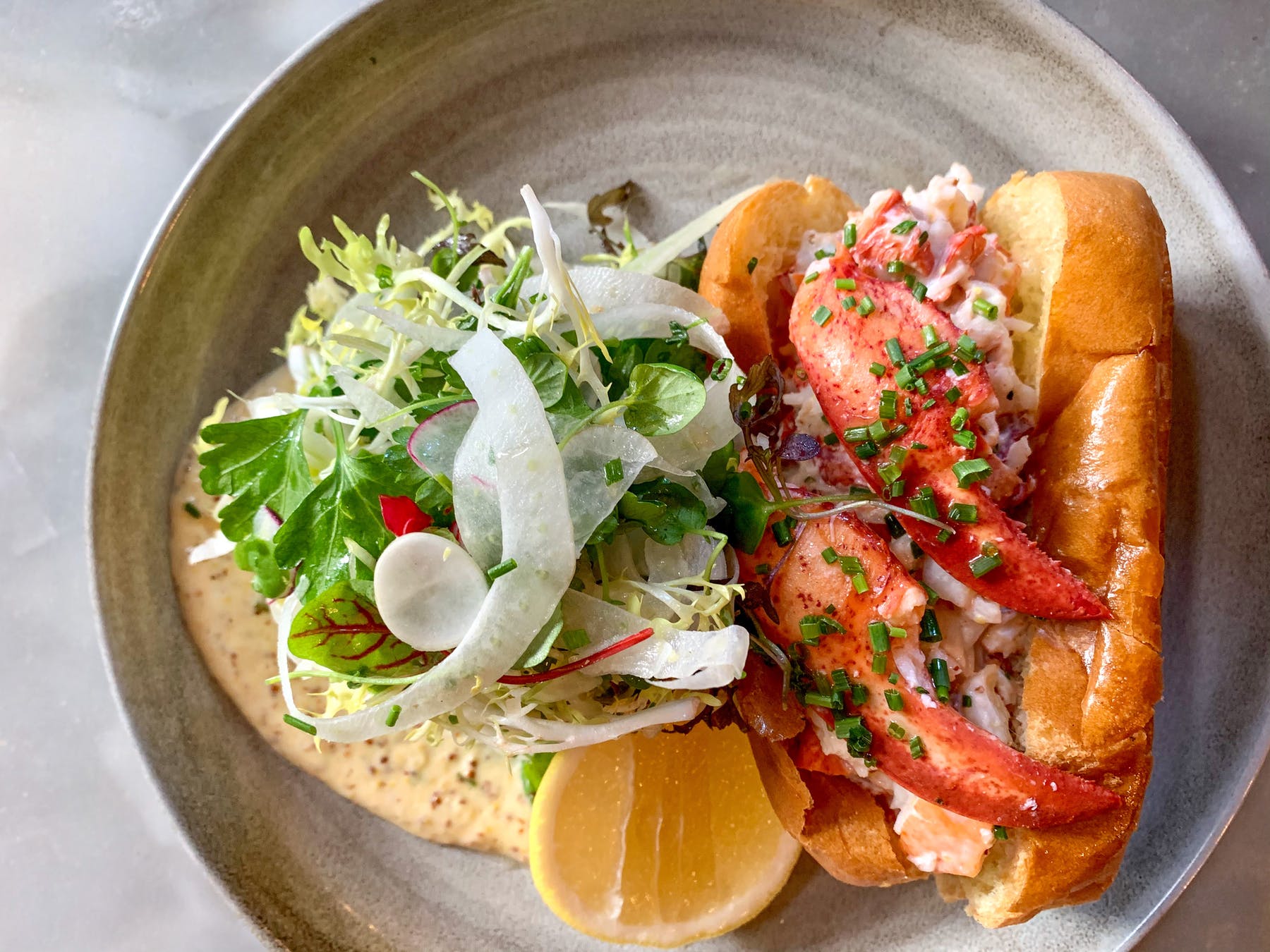 a lobster roll with salad on a plate