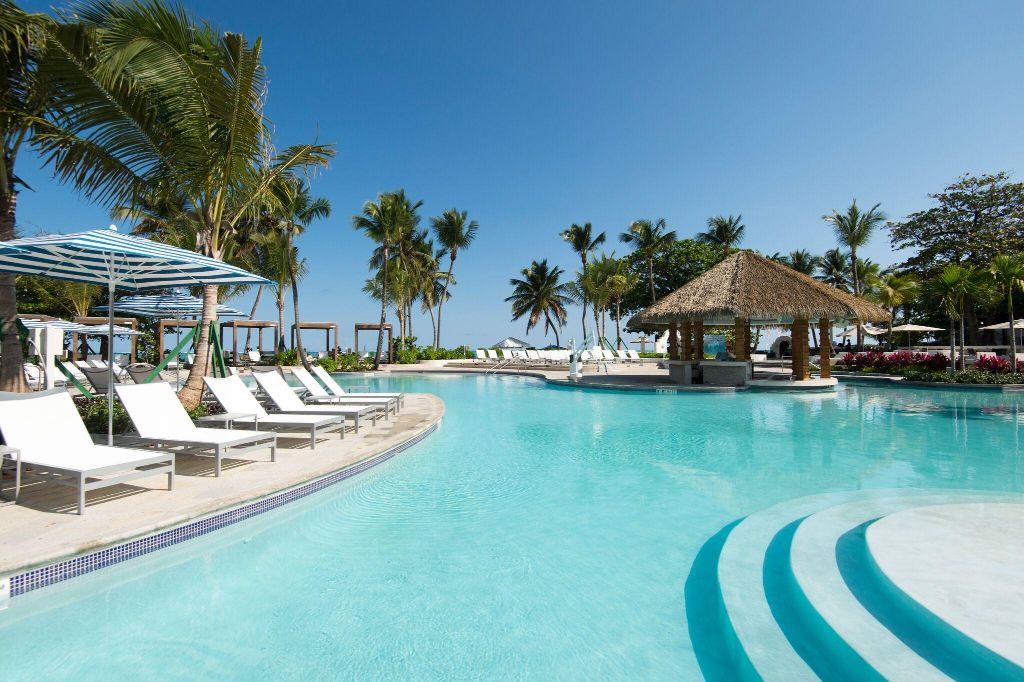 a pool with lounge chairs and a hut