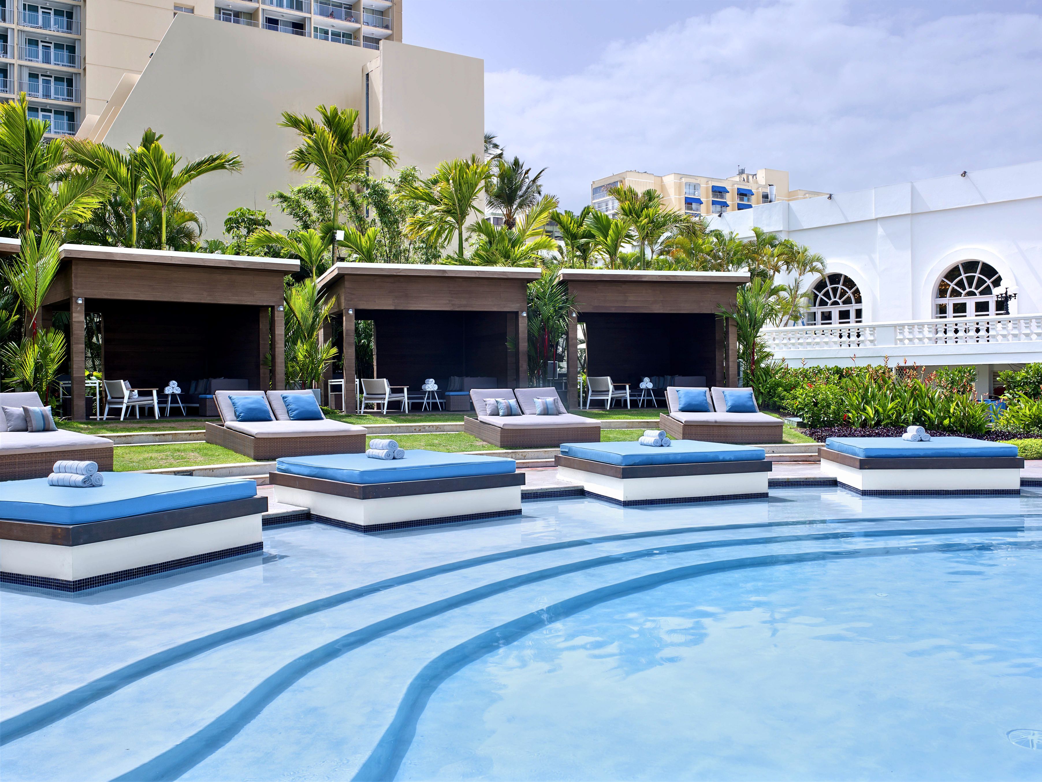 a pool with lounge chairs and a building in the background