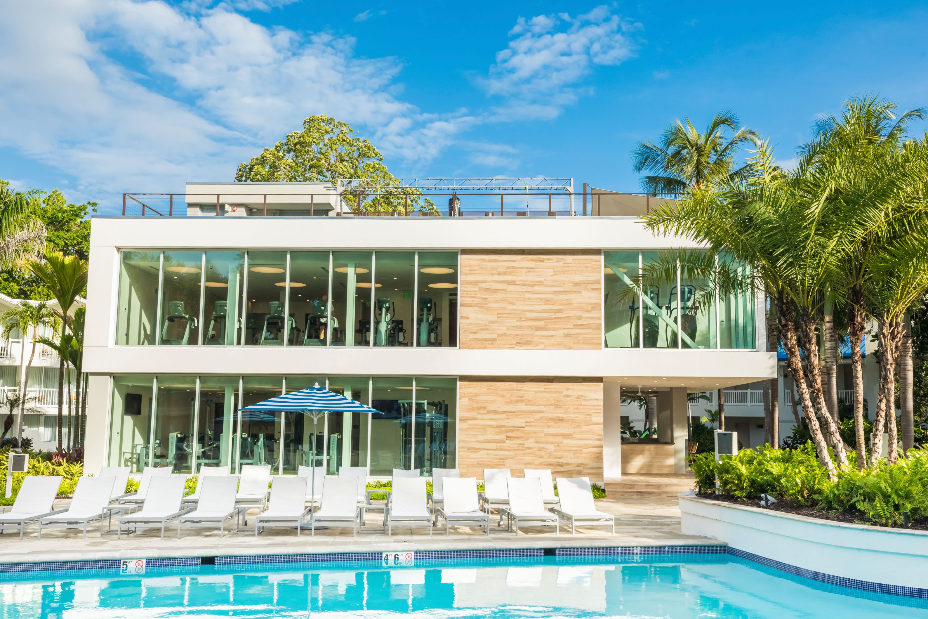 a pool with chairs and a building with trees and blue sky