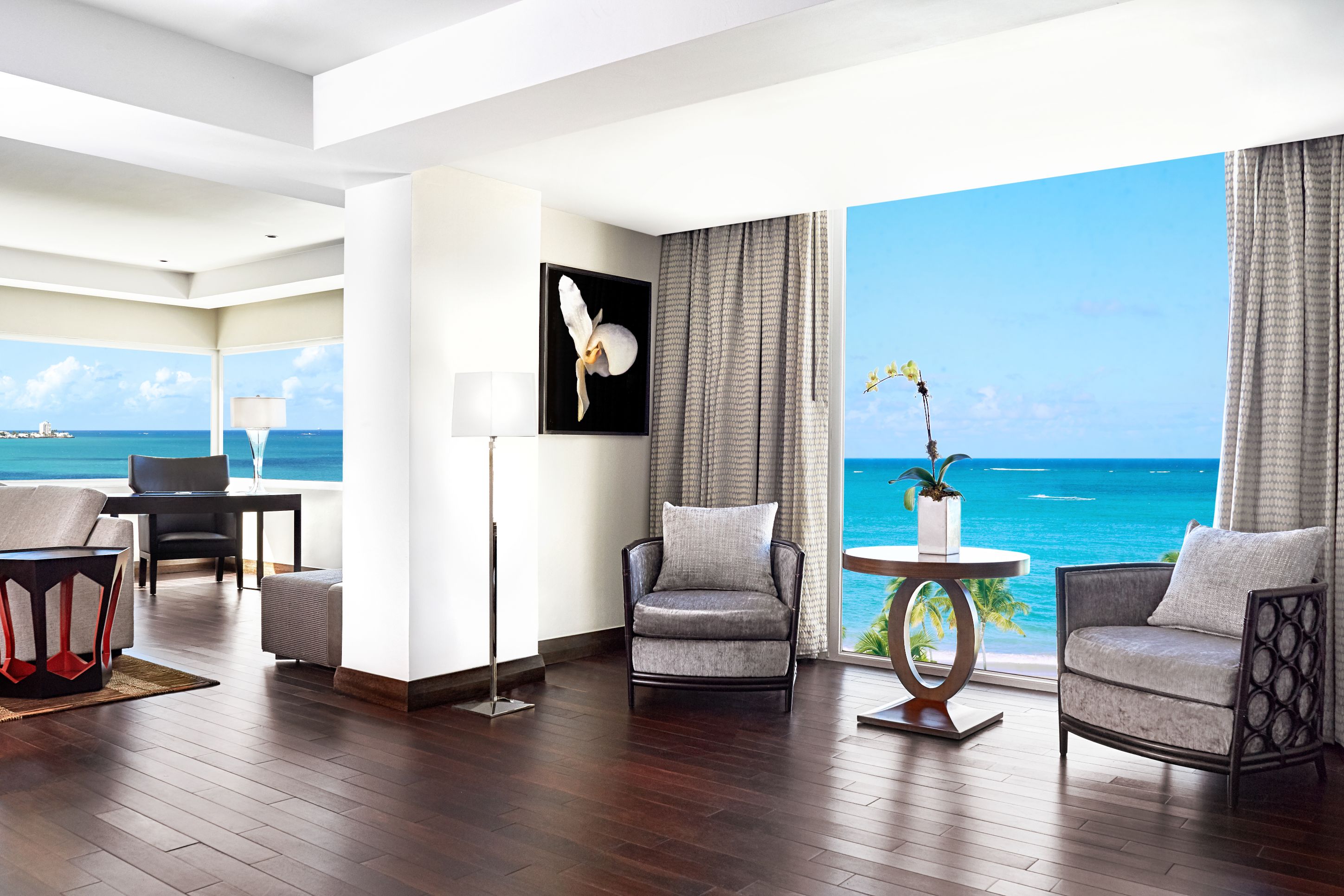 a room with chairs and a table and chairs overlooking the ocean