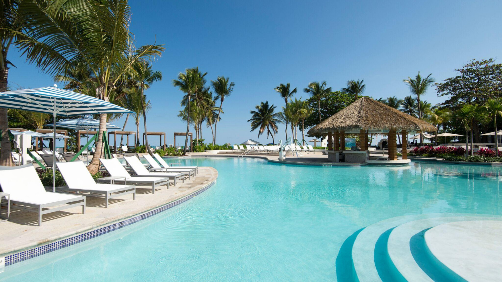 a pool with chairs and a hut