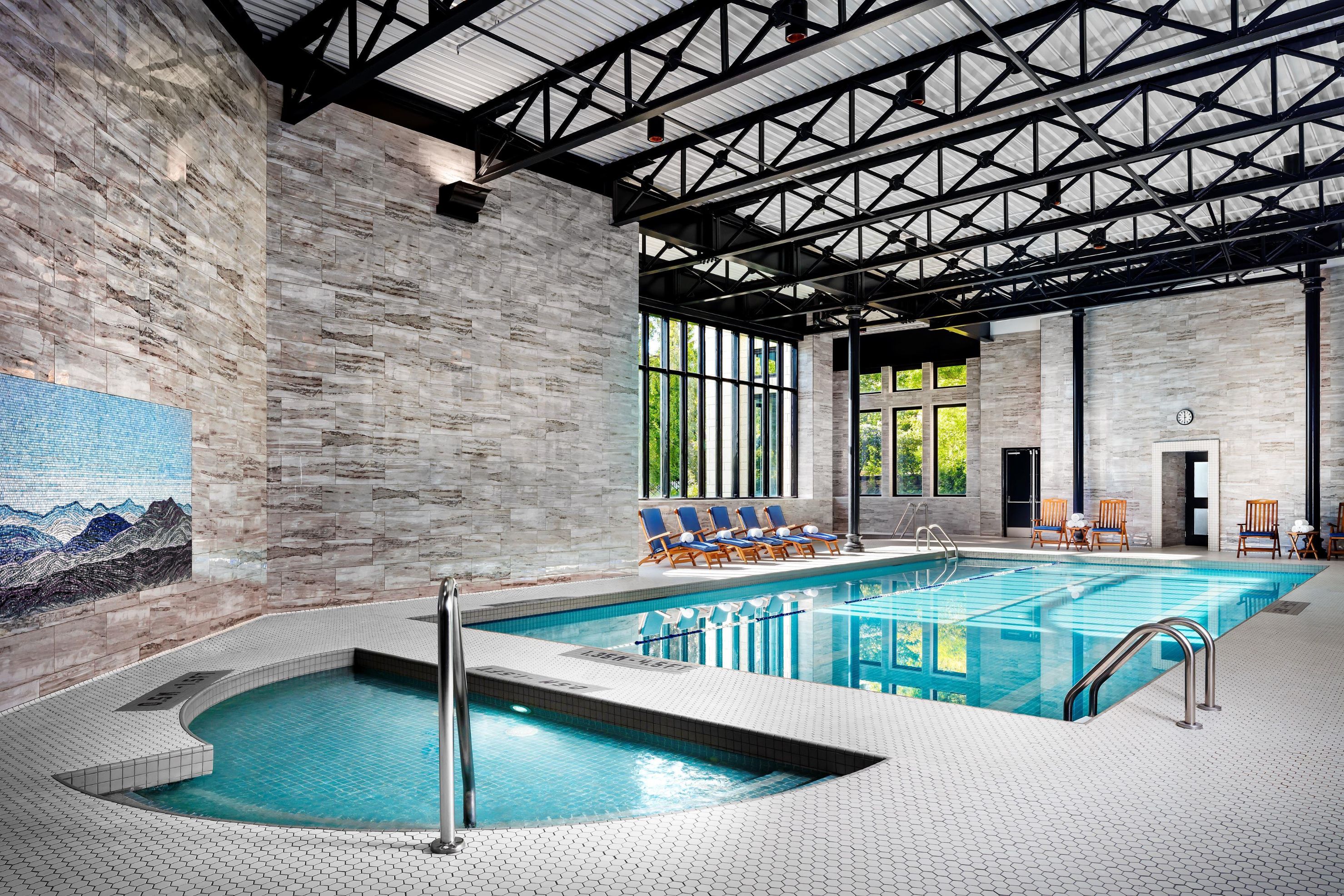 a indoor pool with chairs and a large stone wall