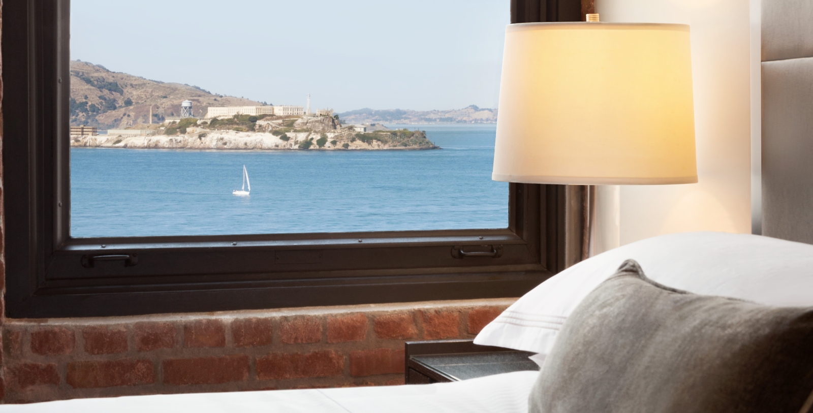 a window with a view of a body of water and a boat in the distance
