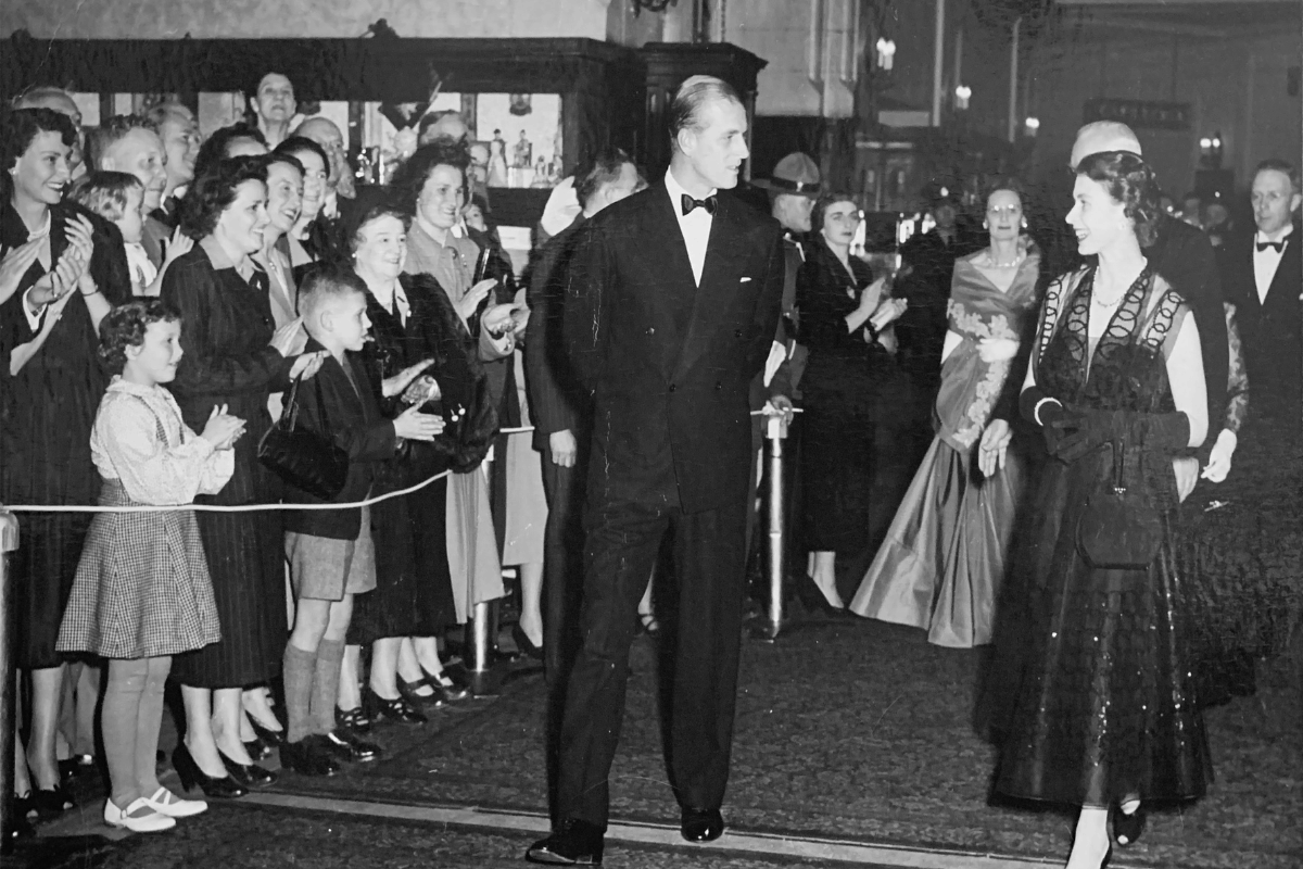 a man in a suit and bow tie walking in front of a crowd