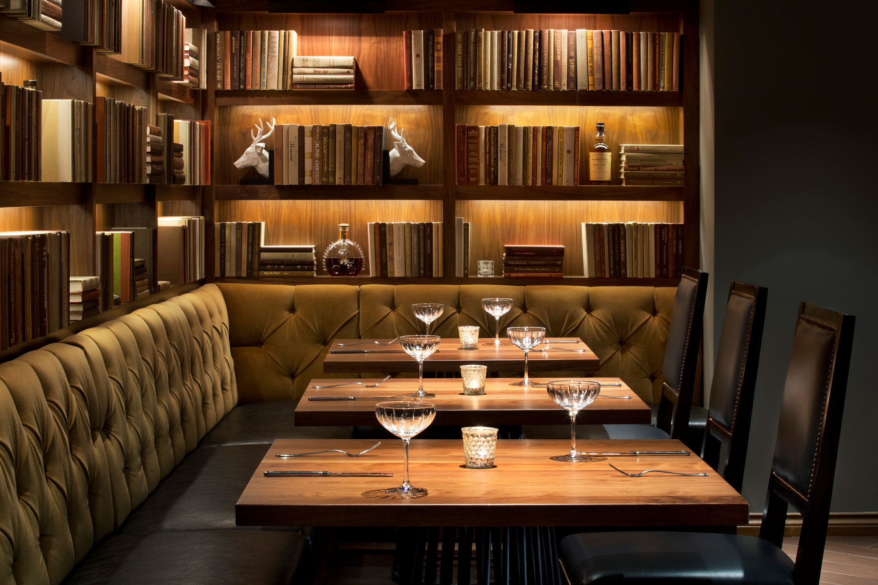 a table with wine glasses and books on the wall