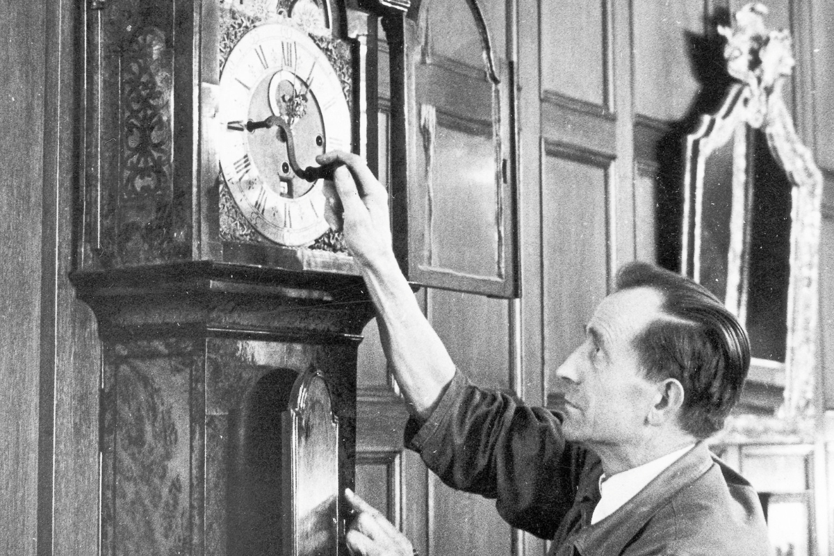 a man holding a pendulum clock