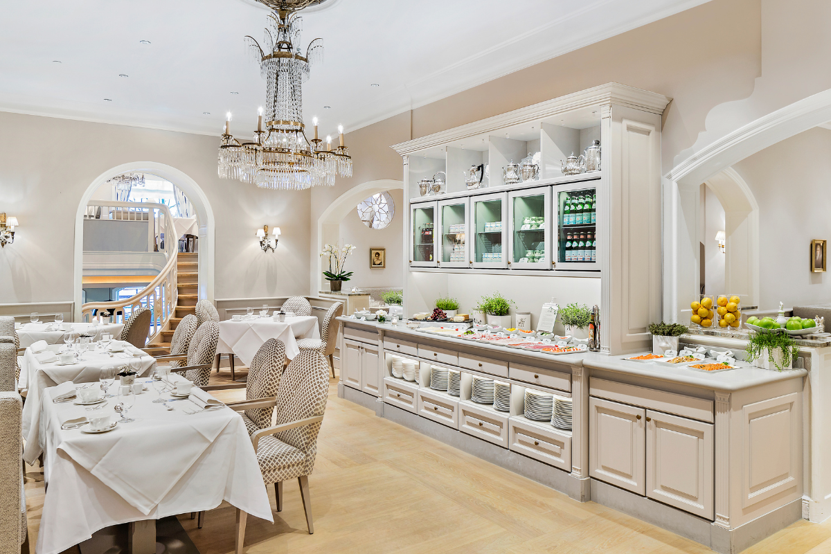 a room with a chandelier and tables and chairs