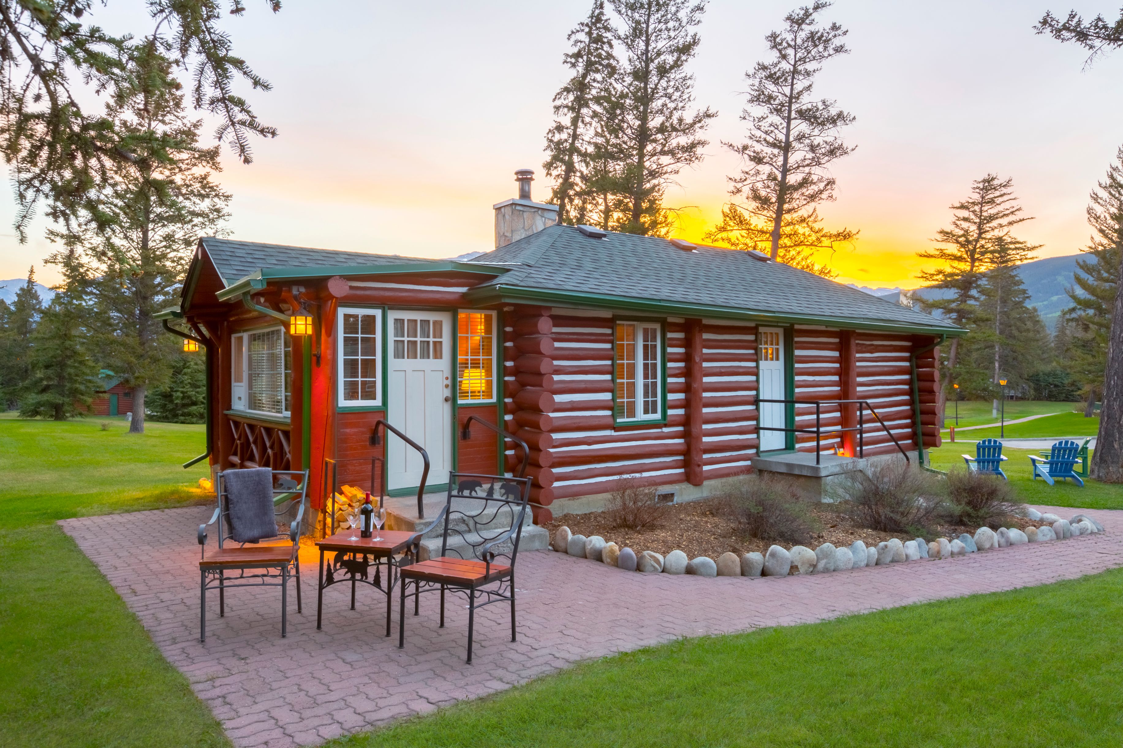 a log cabin with a lawn and a table and chairs