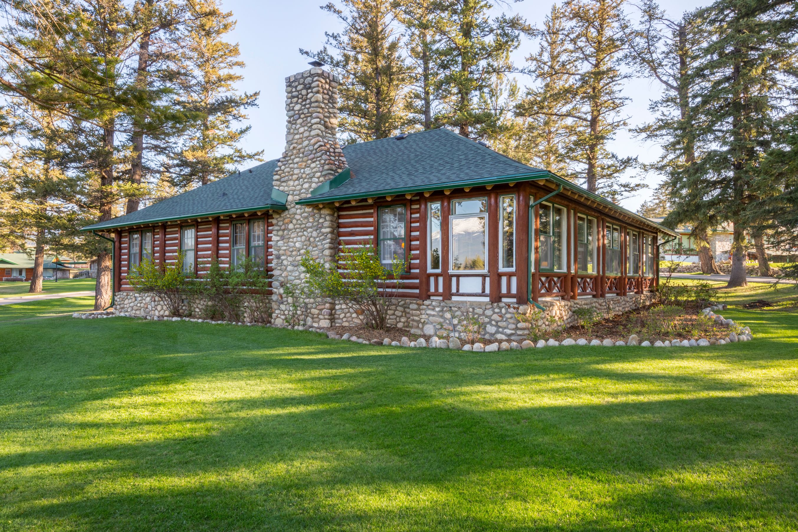 a house with a stone chimney and grass