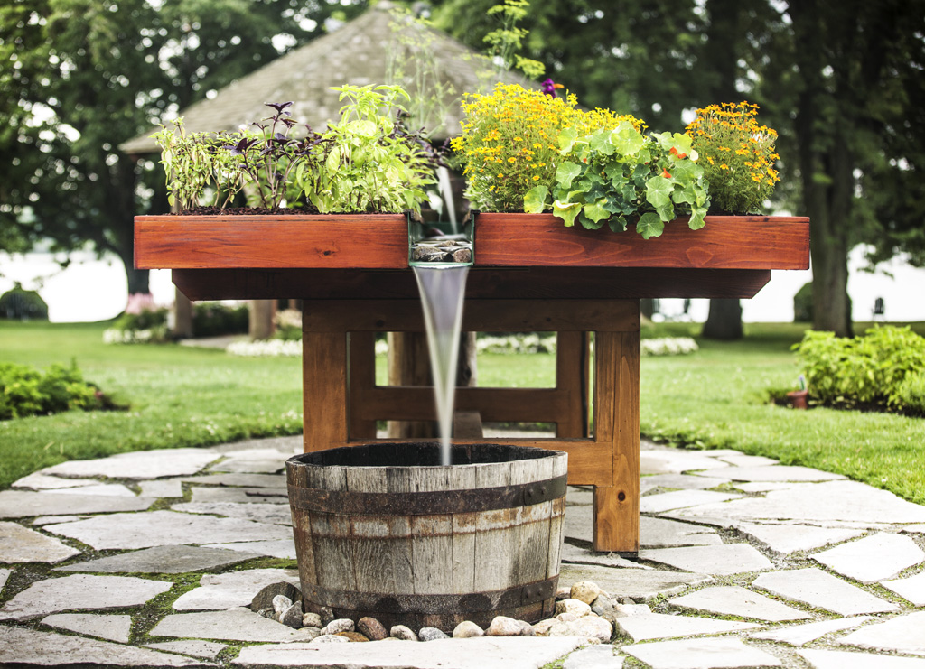 a water fountain with flowers in a wooden barrel