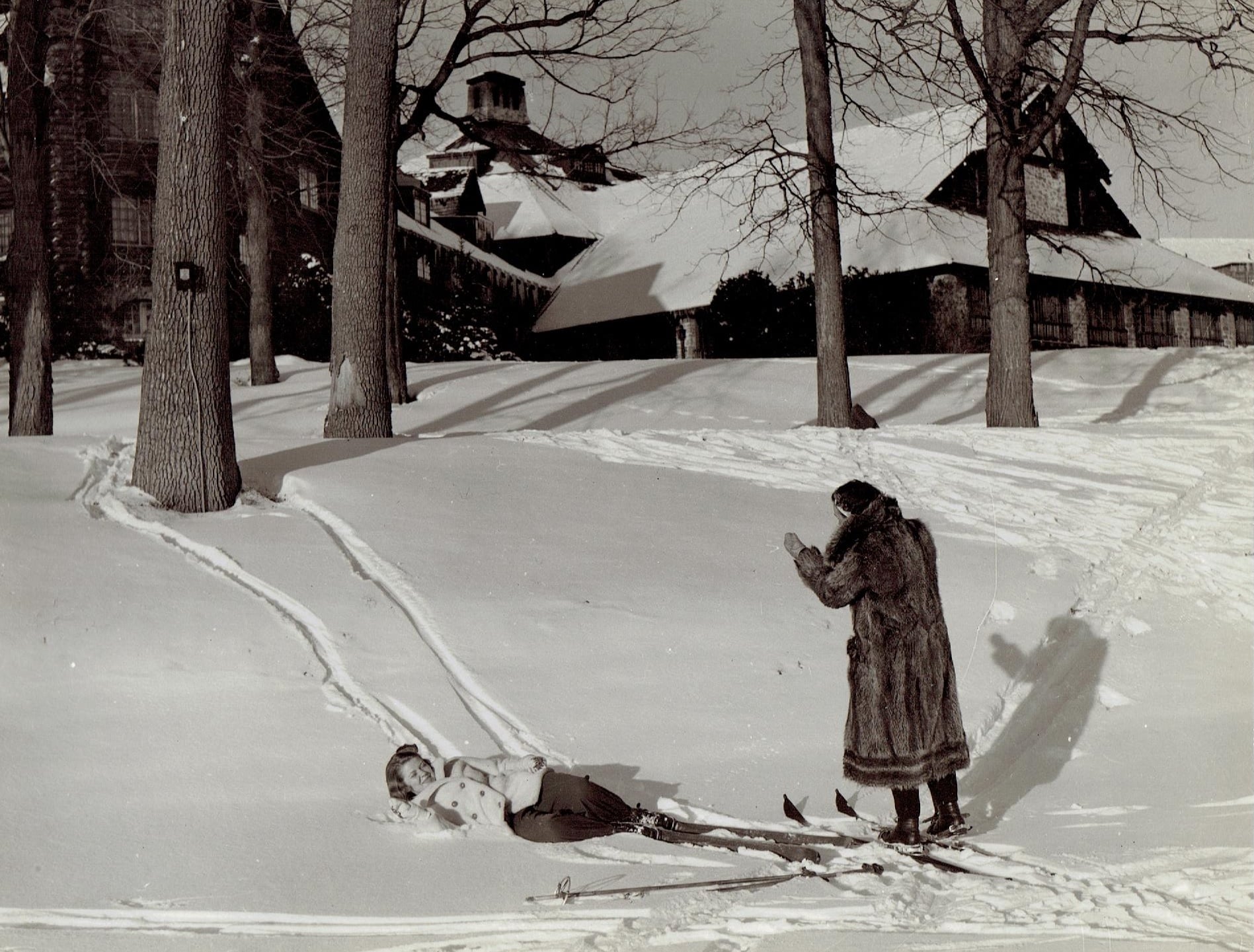 a woman standing in the snow with a child on skis
