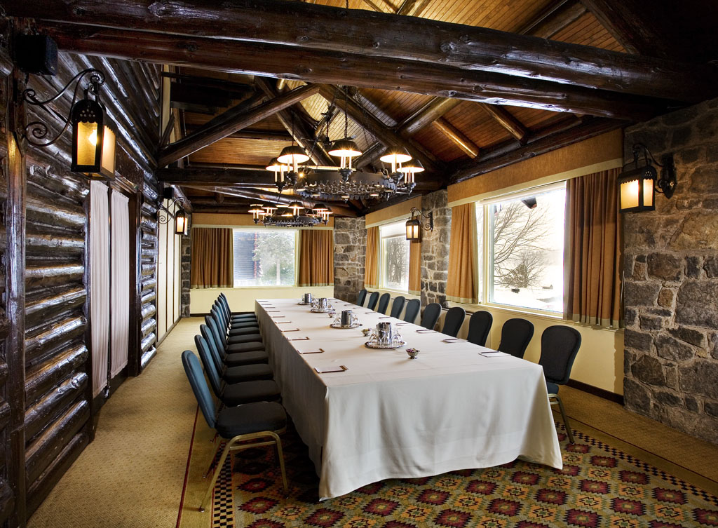 a long table with chairs and chandeliers in a room