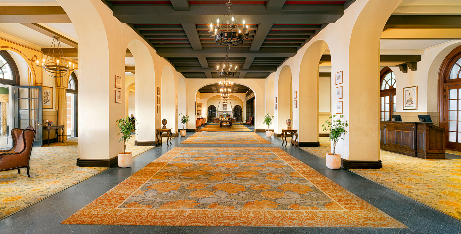 a large hallway with a large rug and chandeliers
