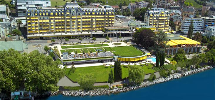 a large building with a lawn and a pool on the edge of a body of water