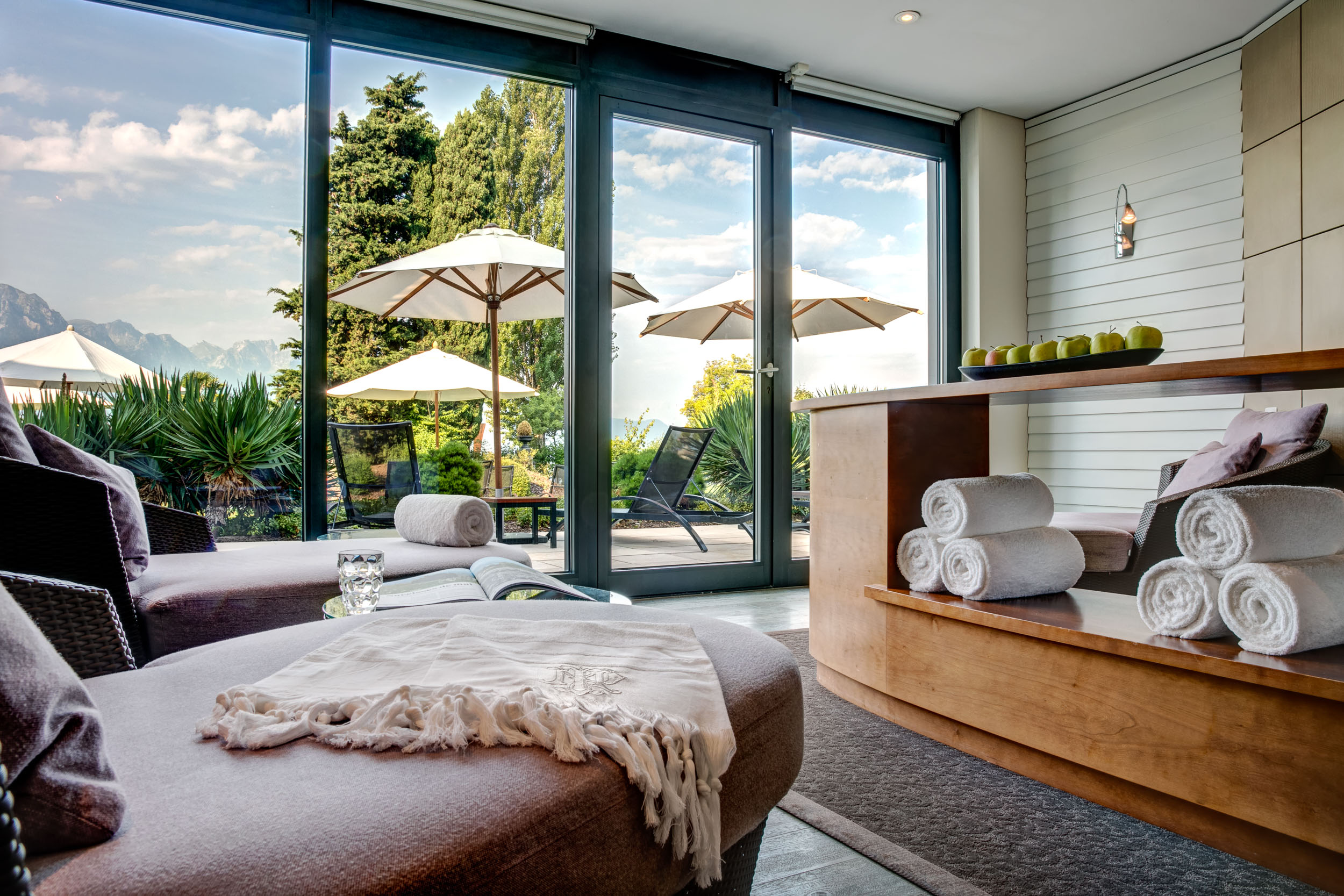 a room with a glass wall and a table with chairs and umbrellas