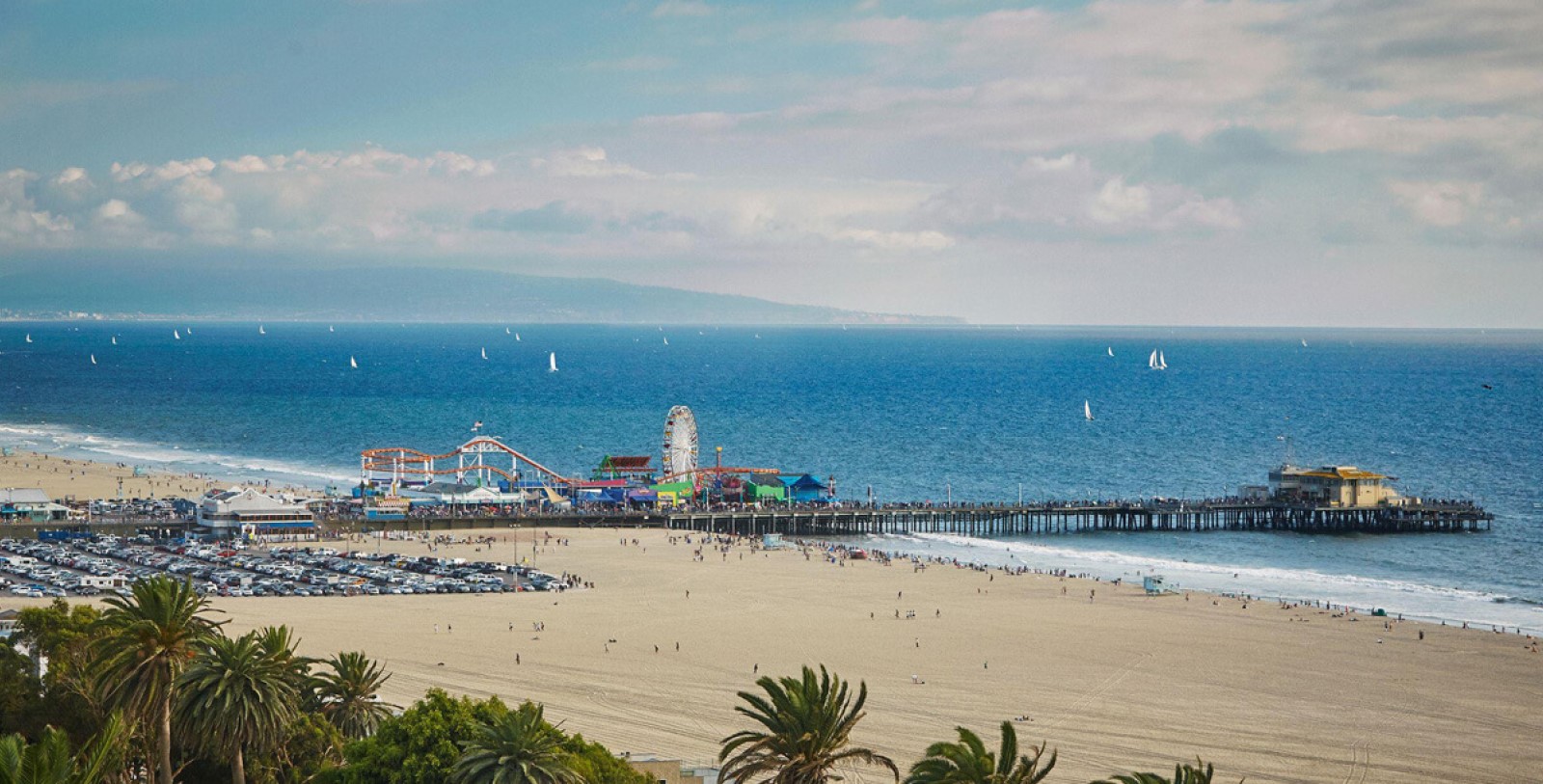 a beach with a pier and a ferris wheel