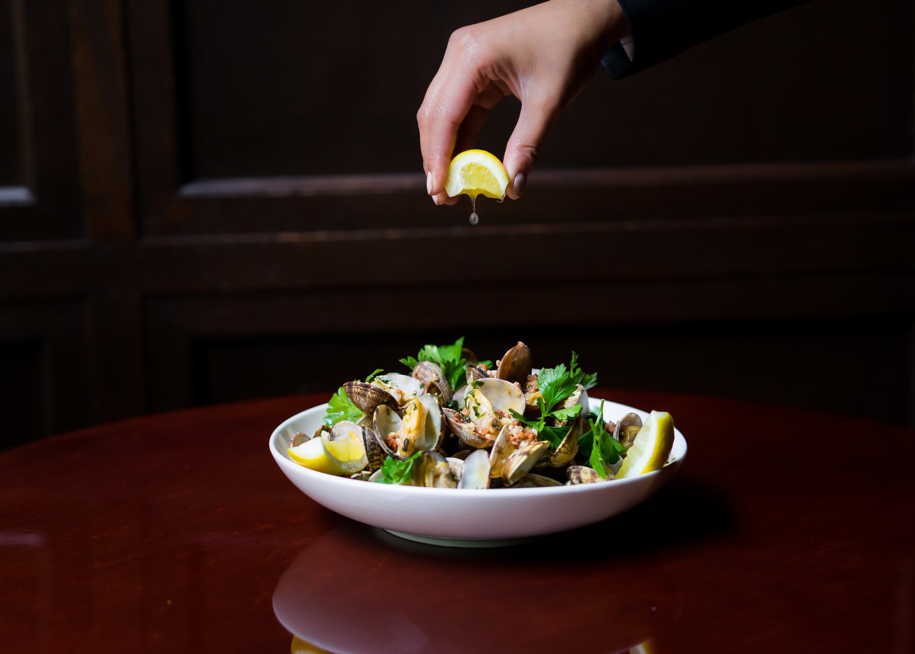 a hand squeezing a lemon over a plate of food