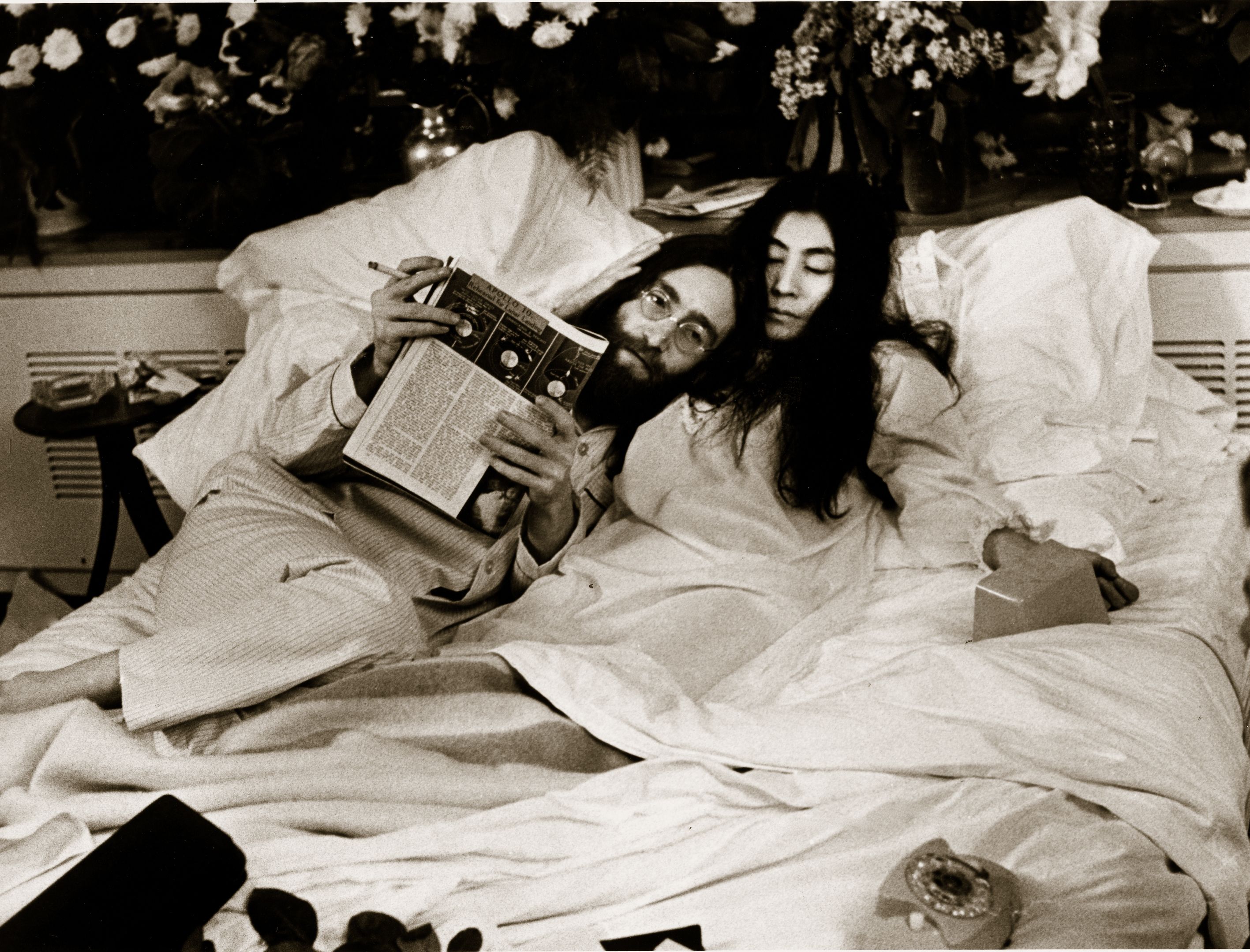 a man and woman lying in bed reading a book