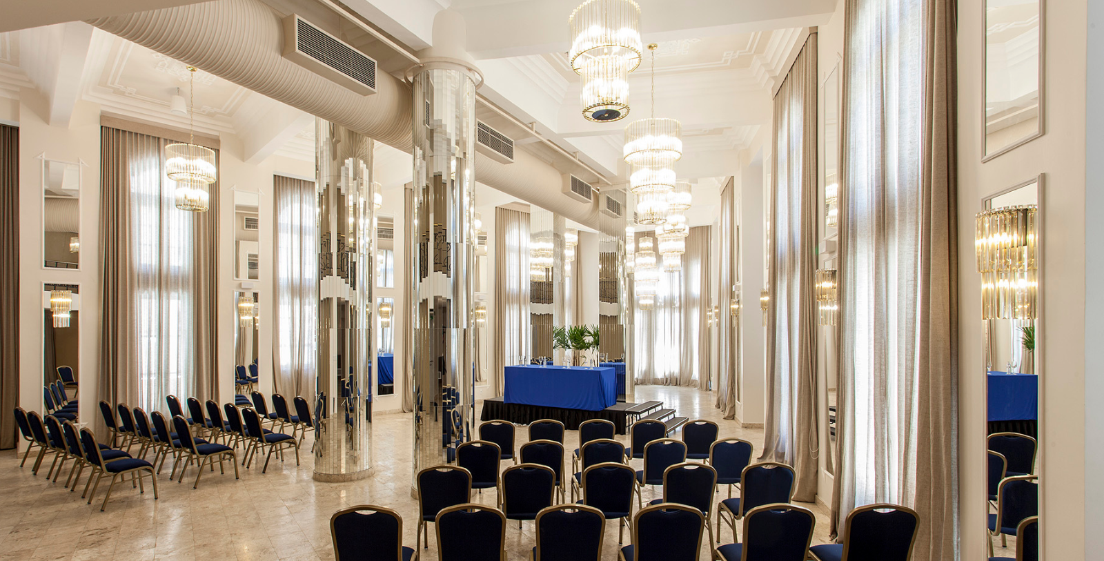 a room with blue chairs and chandeliers
