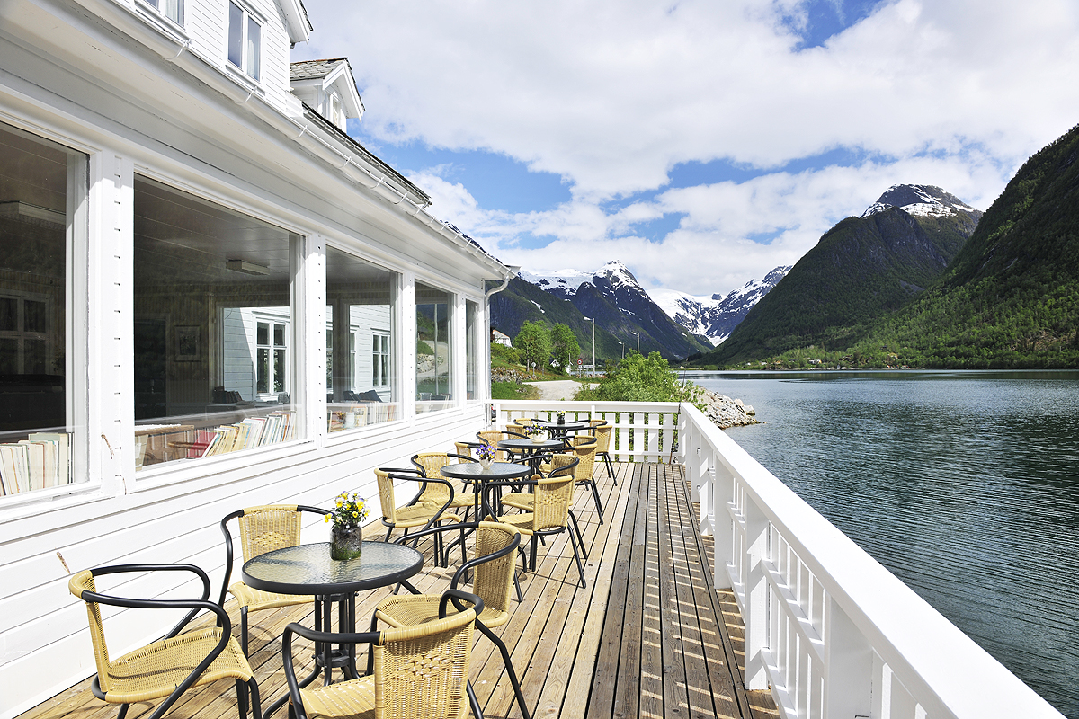 a deck with chairs and tables on it by a lake