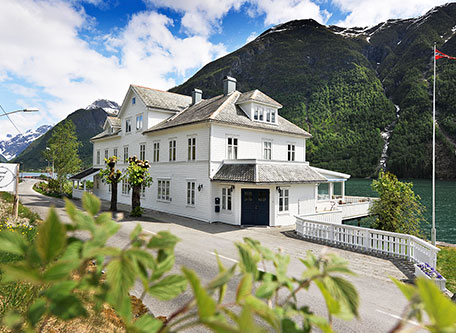 a white house with a lake and mountains in the background
