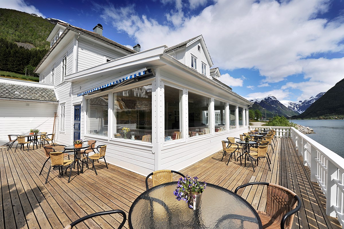 a white building with tables and chairs on a deck