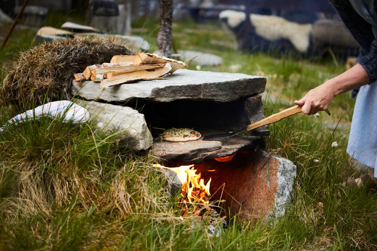 a person cooking pizza on a stone oven