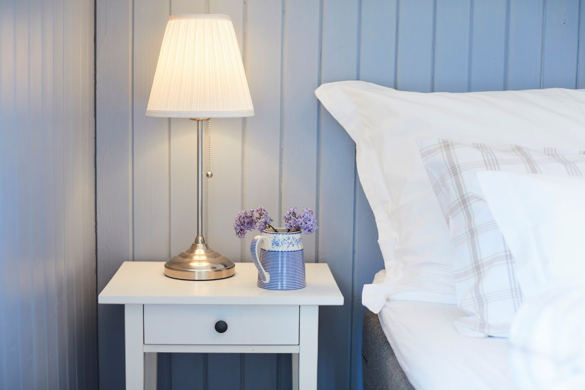 a lamp on a table next to a bed