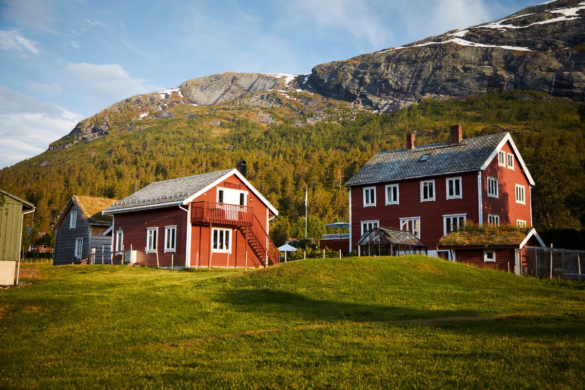 a two red houses in a grassy area with mountains in the background