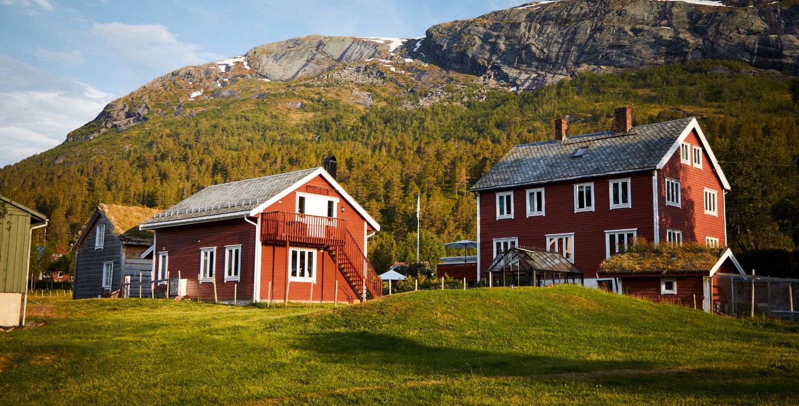 a two red houses in a grassy area with a mountain in the background