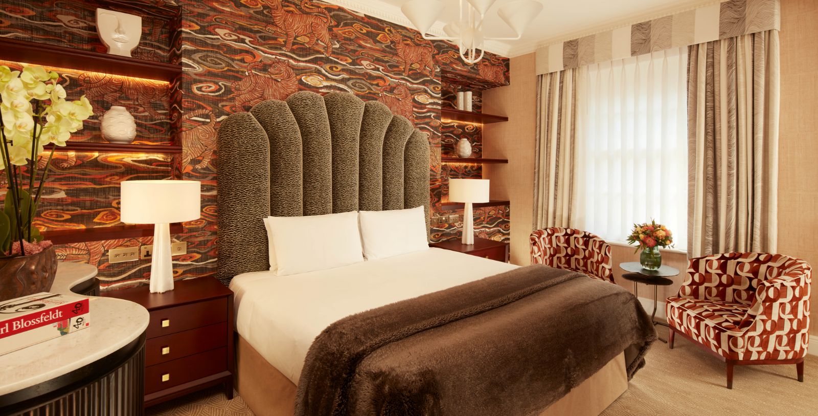 a bed with a brown blanket and a patterned wallpaper