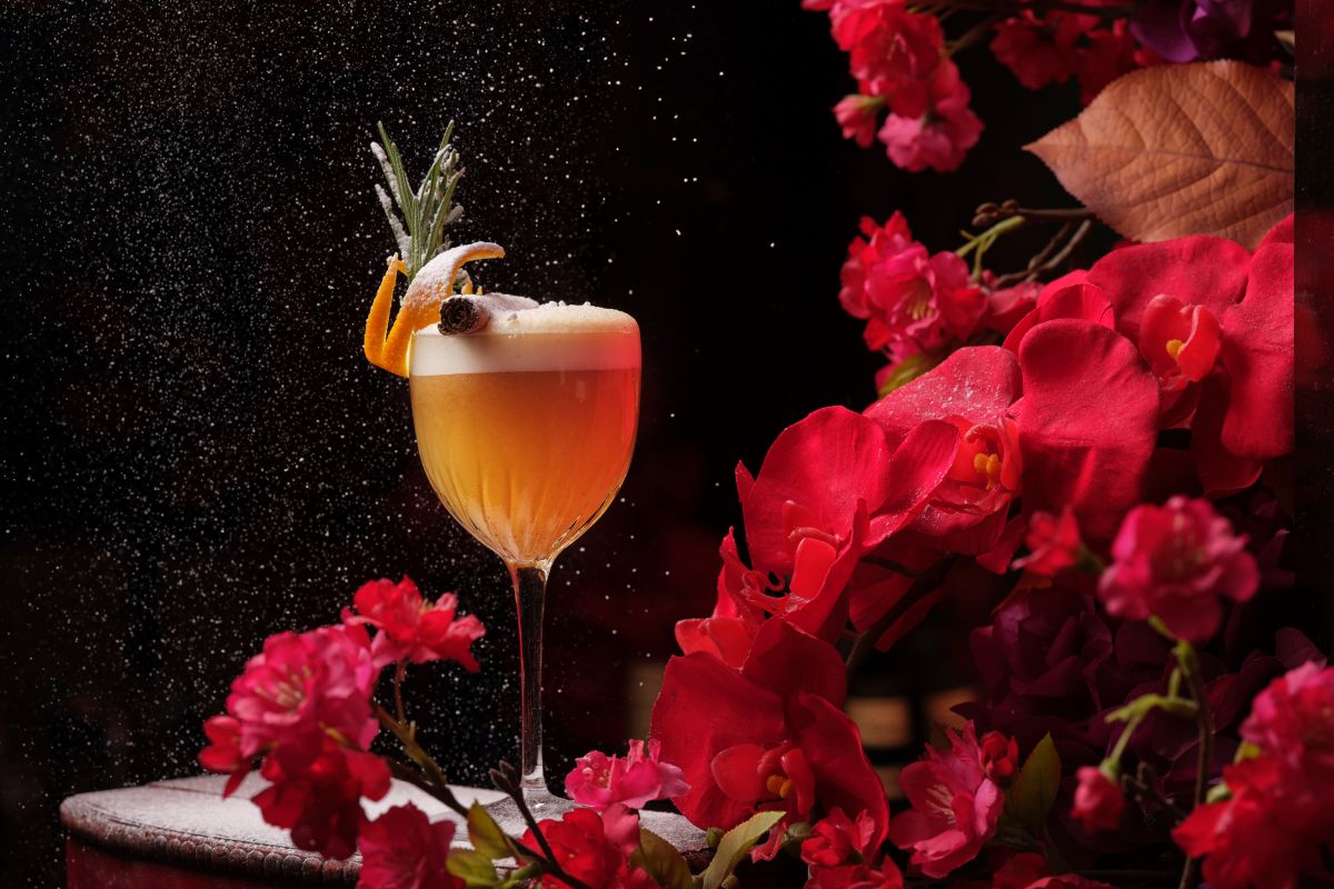 a glass of liquid with a sprinkle of sugar and a flower