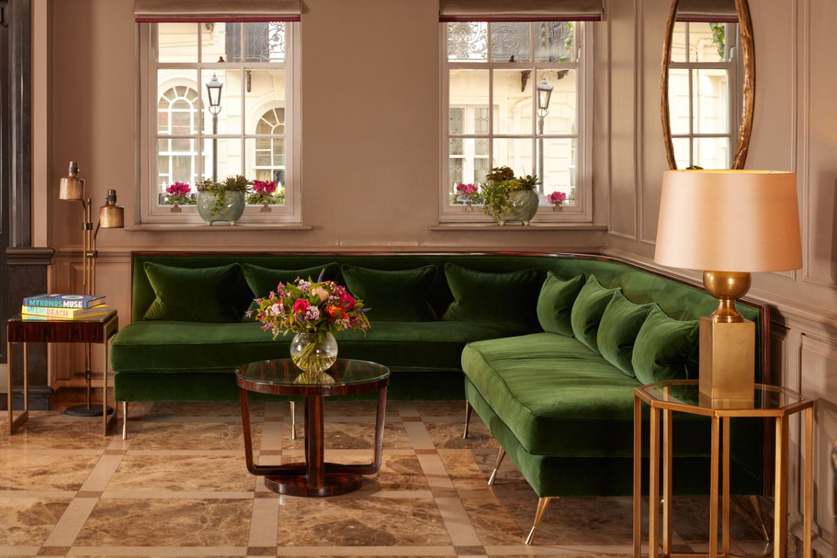 a green couch in a room with windows and a vase of flowers