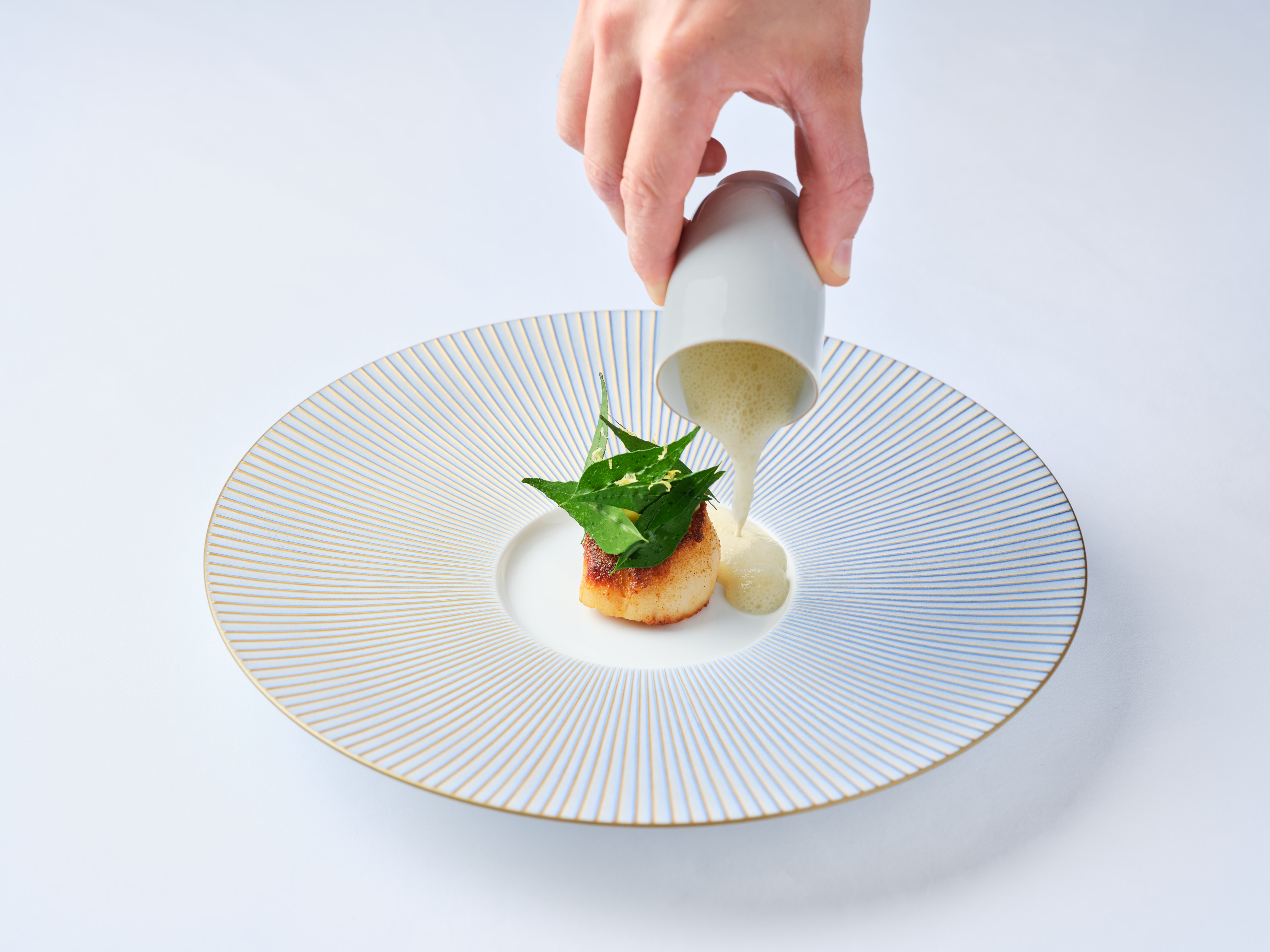 a person pouring sauce onto a plate of food