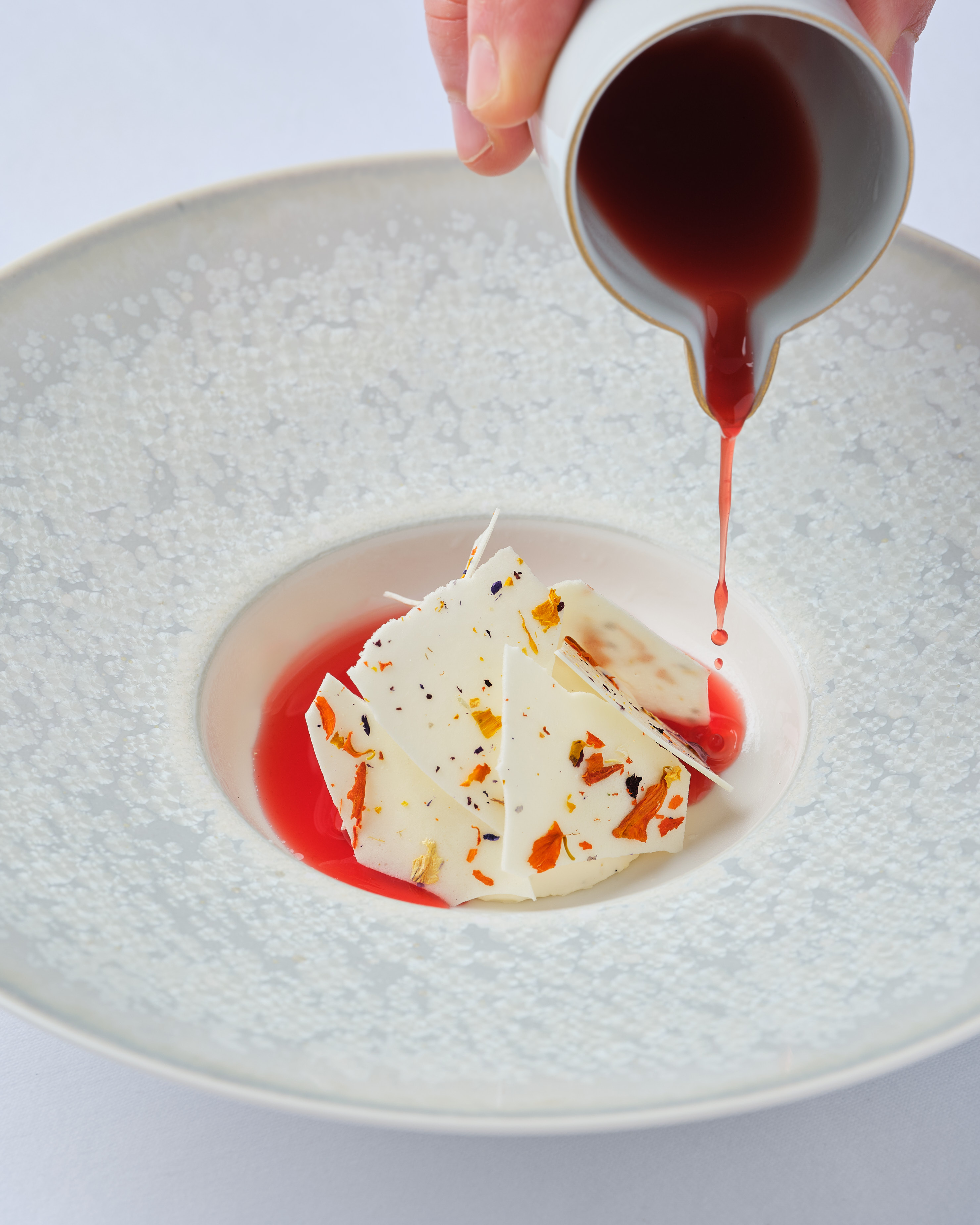 a white plate with red liquid pouring onto a white plate