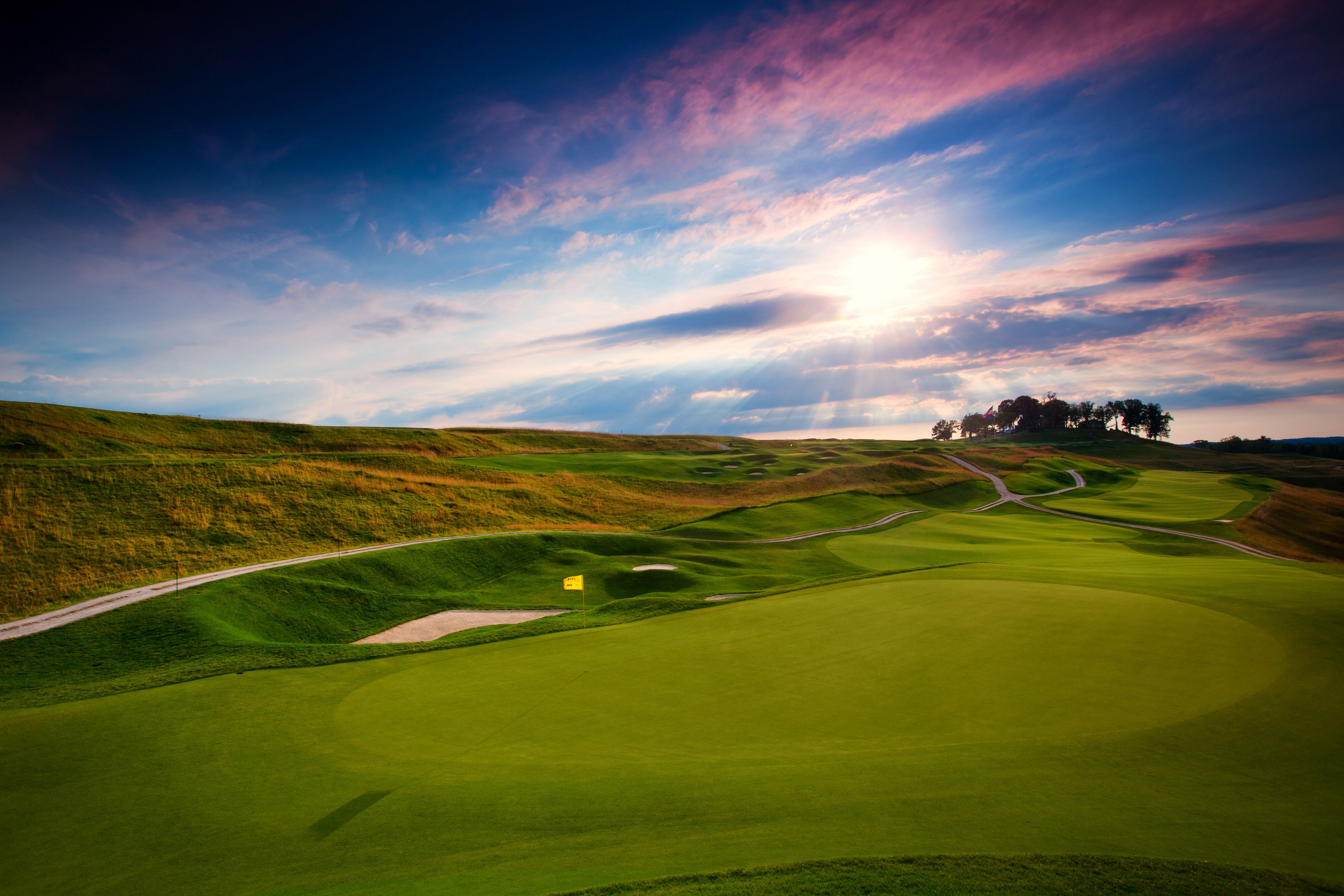 a golf course with a path and a blue sky
