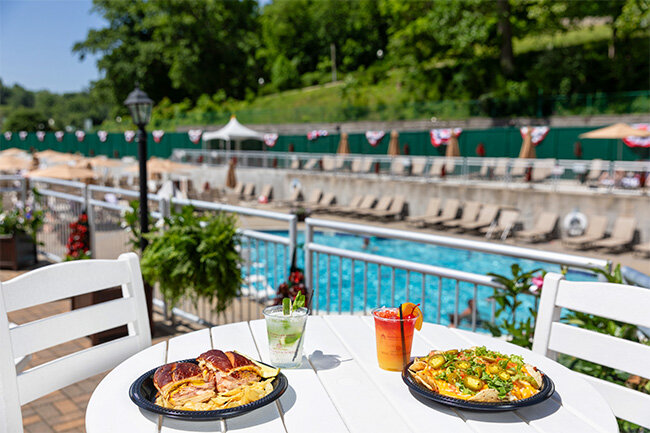 plates of food on a table with a pool in the background