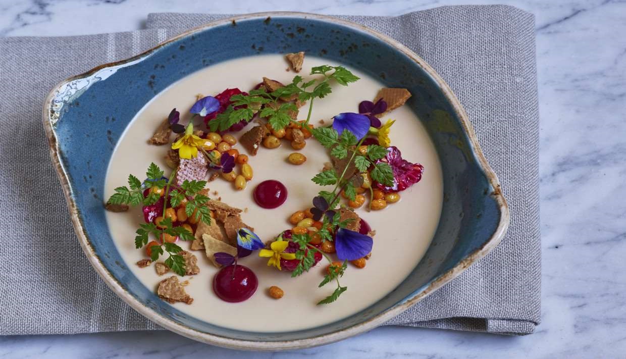 a bowl of soup with flowers and nuts