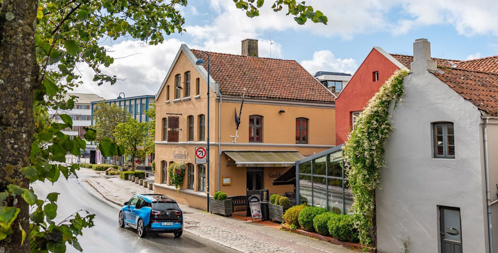 a blue car driving down a street next to a building