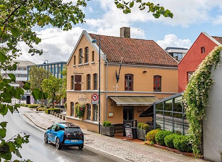 a blue car driving down a street next to a building