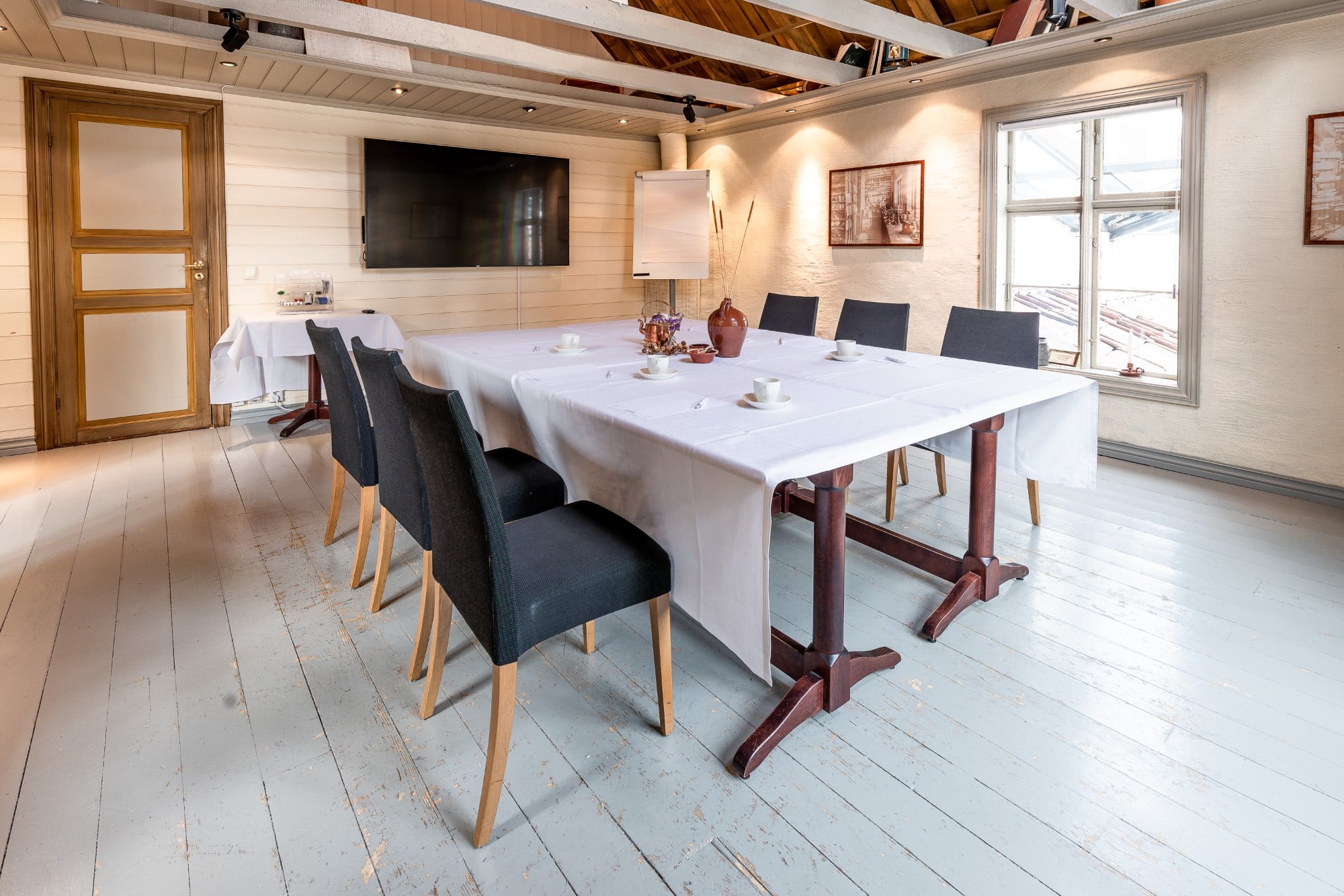 a table with white tablecloths and chairs in a room with a tv