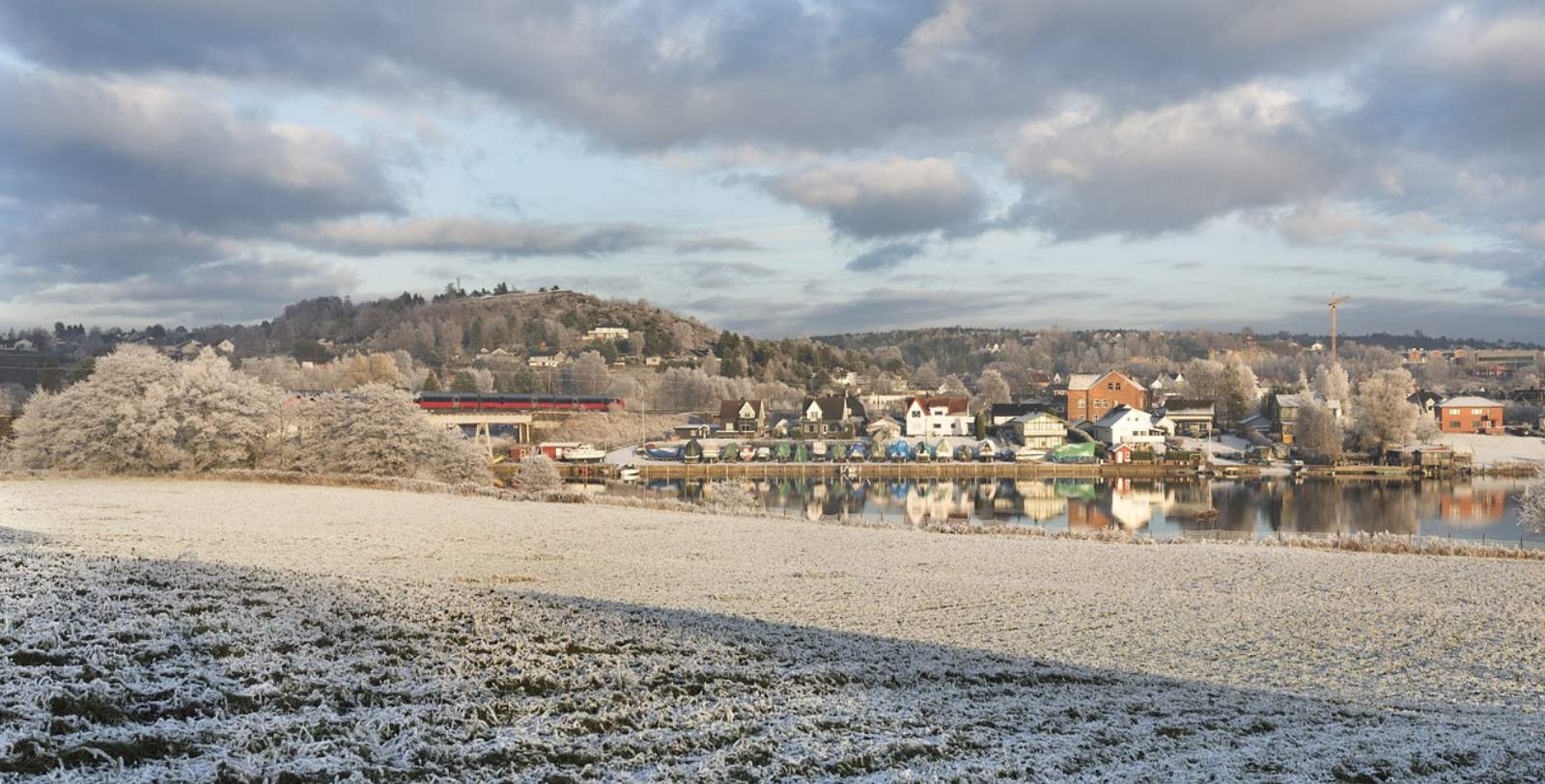 a snowy field with houses and a body of water