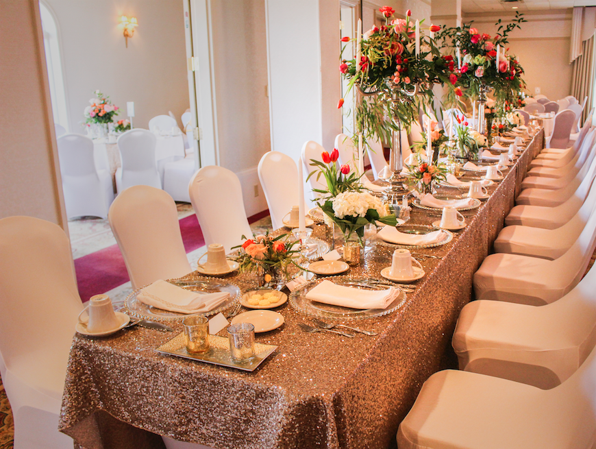 a long table with a gold sequined tablecloth and white chairs